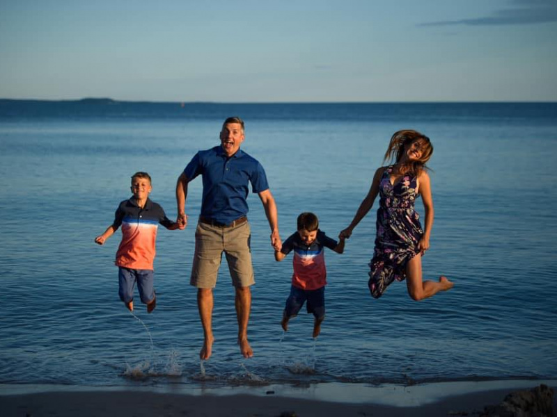 Ben Davis, Hubbards Streetscape committee member, jumping and posing with two sons and wife on the beach.