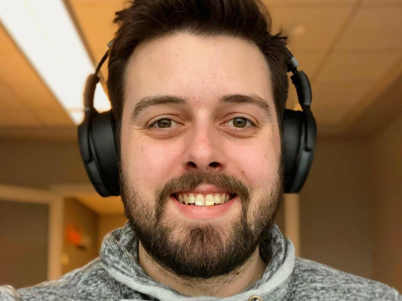 Matthew Burke, a young man, smiling for the camera with headphones on.