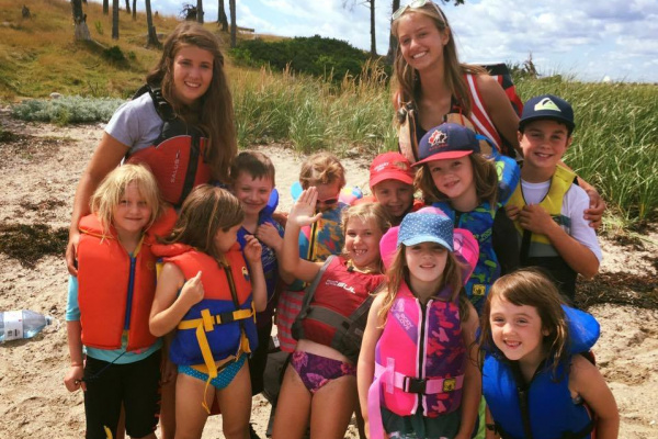 Sarah Doane, smiling happily with a group of young children, ranging in age, attending the Hubbards Sailing Club.