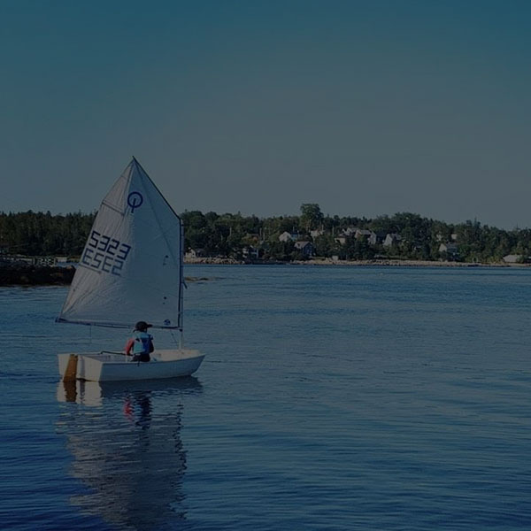 Opti sailing in Hubbards Cove on clear day.